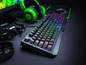 Eine Razer-Tastatur mit RGB-Beleuchtung, grünem Headset und einer Maus auf einem Schreibtisch.