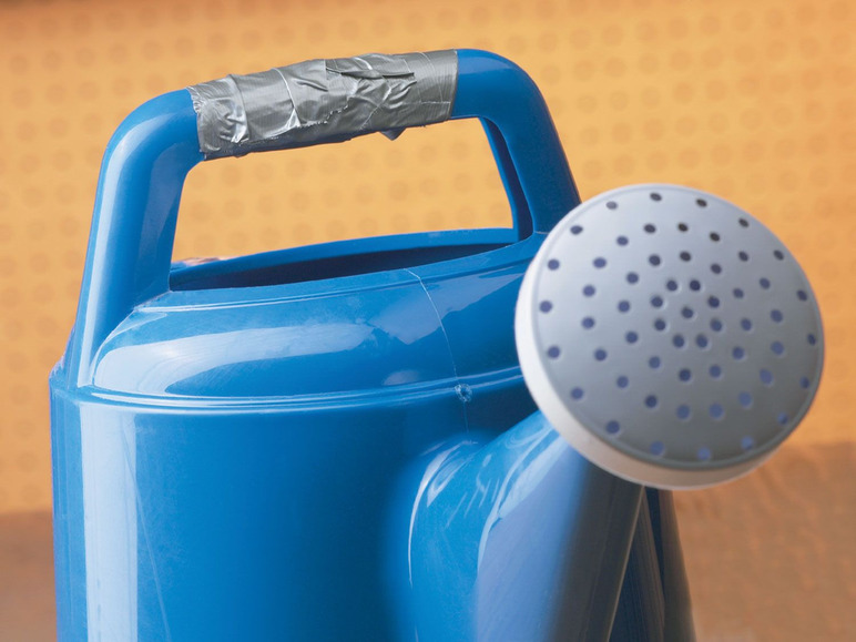 Eine blaue Gießkanne mit einem kaputten Griff, der mit Klebeband repariert wurde