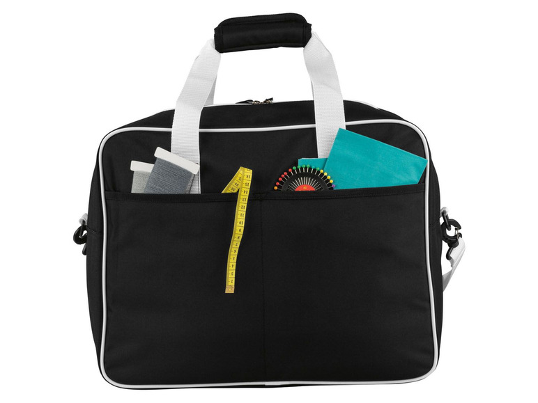 Eine schwarze Reisetasche mit einem Maßband, Nadeln und Garn.