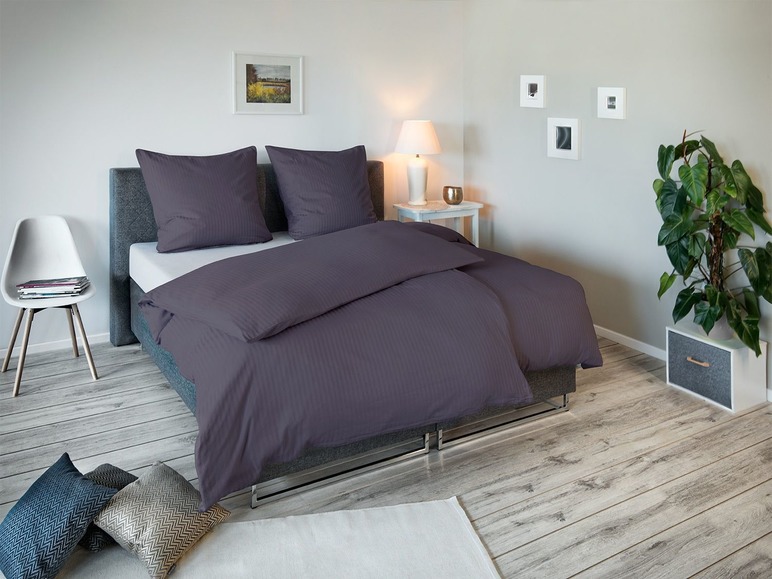 Dunkelgraue Bettwäsche mit gestreiftem Bettbezug auf einem Bett in einem Schlafzimmer.