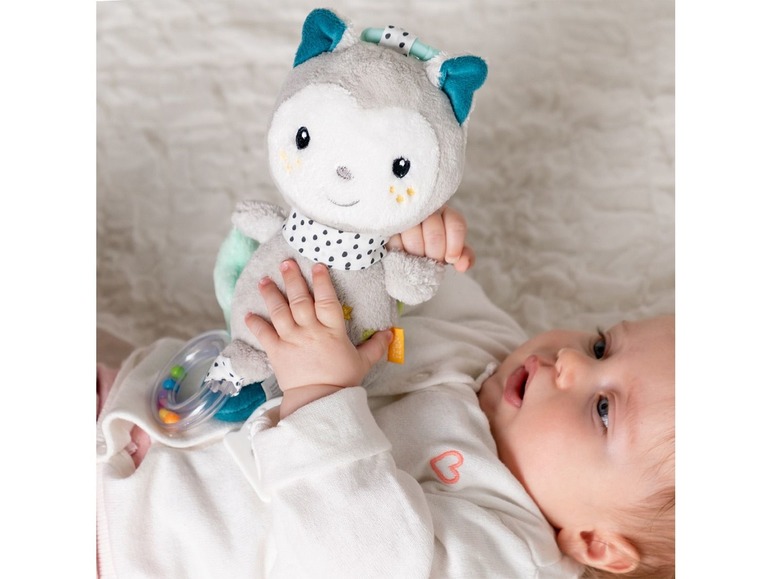 Ein Baby spielt mit einem grauen Plüschtier und einem Beißring.