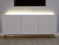 Weißes TV-Lowboard mit goldenen Beinen und LED-Beleuchtung.