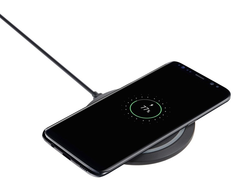 Ein schwarzes Samsung-Smartphone wird drahtlos auf einer schwarzen Ladestation geladen.