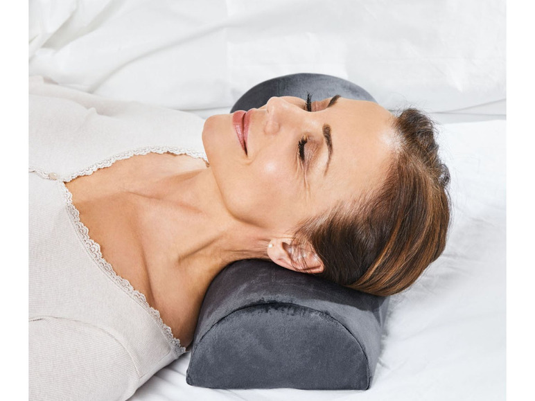 Frau, die auf dem Rücken mit einem Nackenkissen liegt.