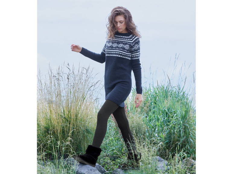 Eine Frau trägt ein schwarzes Strickkleid mit skandinavischem Muster und Ugg-Stiefeletten.