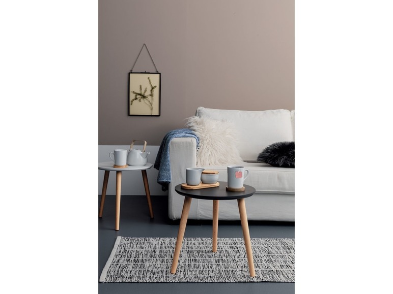 Zwei Holz-Couchtische mit Tassen, einer Teekanne und einem Zuckertopf in einem Wohnzimmer.