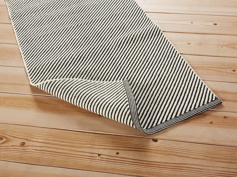 Ein gestreiftes Teppich mit schwarzen Streifen auf einem Holzboden.