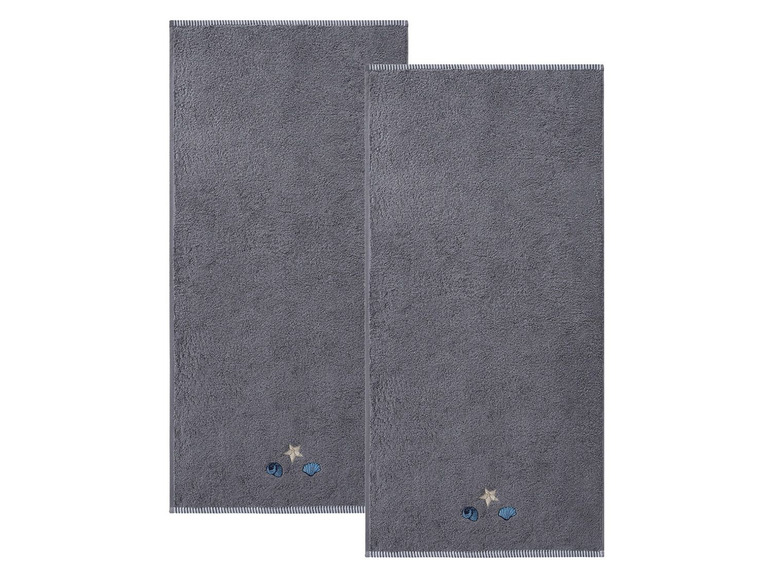 Zwei graue Handtücher mit Muschel- und Sternmotiv.