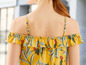Ein gelbes Oberteil mit tropischem Muster und Rüschen.