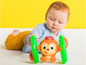 Ein Baby spielt mit einem Bright Starts Spielzeug, einem Affen mit Ringen.