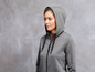 Eine Frau trägt einen grauen Hoodie mit Kapuze.