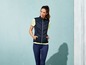 Eine Frau in einer schwarzen Steppweste und blauen Leggings.