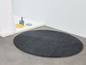 Eine dunkelgraue, runde Badematte in einem Badezimmer.