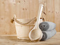 Ein Holzfass, eine Schöpfkelle und Handtücher in einer Sauna.