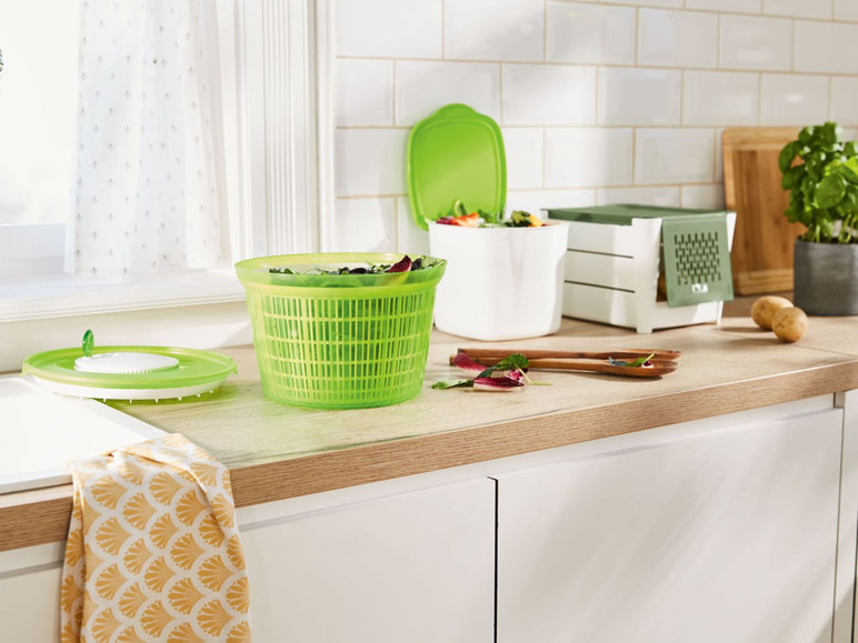 Ein grüner Salatschleuder auf einer Küchenarbeitsplatte mit anderem Küchenzubehör.