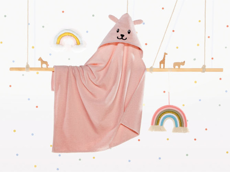 Ein rosa Bademantel mit Tierkapuze, zwei Regenbögen und eine Holzgiraffe.