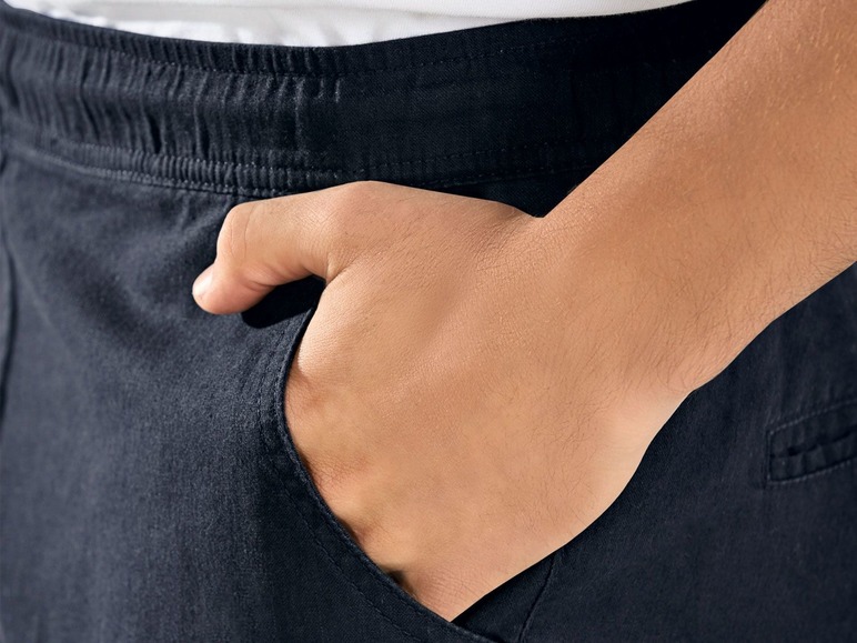 Hand in der Tasche einer schwarzen Hose.