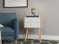 Ein Holz-Nachttisch mit zwei weißen Schubladen und einem blauen Sessel.