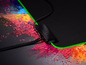 Eine Razer-Mausmatte mit grüner Beleuchtung vor einem Hintergrund aus Farbpulver.