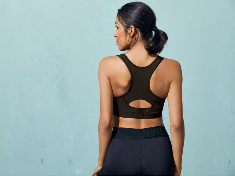 Eine Frau trägt einen schwarzen Sport-BH und Leggings mit dem Logo 'Love'.
