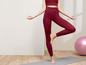 Frau in roten Yoga-Leggings steht auf einer Matte.