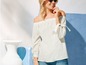 Frau in einem weißen Off-Shoulder-Top mit blauen Jeans.