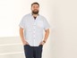 Mann in einem weißen Hemd mit Punkten und blauen Hosen.