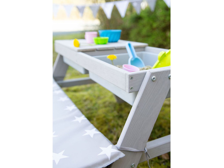 Ein Holzspieltisch mit Sandkasten und einer Bank mit Sternenmuster.