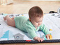 Baby auf einer Tiny Love Spielmatte mit verschiedenen Aktivitäten.