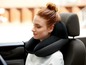 Eine Frau in einem Auto mit einem schwarzen Nackenstützkissen.