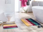 Badezimmer mit freistehender Badewanne, Toilette und zwei bunten Badvorleger