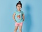 Ein Mädchen trägt ein hellblaues T-Shirt mit Paw Patrol Aufdruck und rosa Shorts.