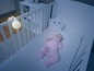 Ein Baby in einem Kinderbett mit einer Nachtlampe in Form eines Schafes.