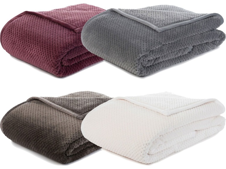 Vier gefaltete Fleece-Decken in verschiedenen Farben.