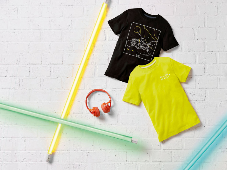 Zwei T-Shirts, ein schwarzes mit einem „Space“-Print und ein gelbes mit „billions of miles“, mit Neonlicht und Kopfhörern.