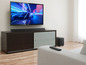 Ein Fernseher mit Soundbar und Subwoofer in einem Wohnzimmer.