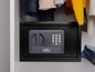 Ein schwarzer Tresor mit digitalem Tastenfeld von Burg Wachter in einem Kleiderschrank.