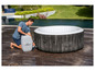 Ein Mann bläst ein aufblasbares Whirlpool Lay-Z-Spa im Garten auf.