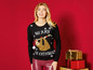 Frau mit einem Weihnachtspullover mit einem Faultier und dem Schriftzug 'Merry Slothmas'.