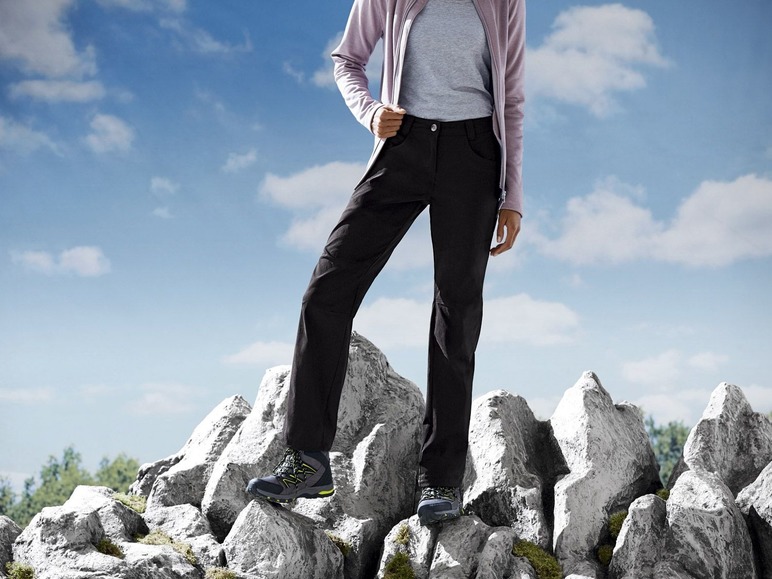 Schwarze Hose und Wanderschuhe auf felsigem Gelände.