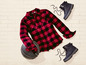 Ein rot-schwarzes Karohemd, ein Basketball und zwei Paar schwarze Stiefel.