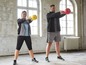 Zwei Personen trainieren mit Kettlebells im Fitnessstudio.