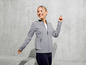Eine Frau trägt eine graue Trainingsjacke und schwarze Leggings.