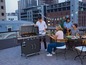 Eine Gruppe Freunde grillt auf einem Balkon mit einem Weber Gasgrill.