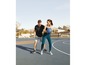 Ein Mann und eine Frau spielen Basketball auf einem Außenplatz.
