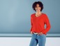 Frau in einem roten Pullover und blauen Jeans.