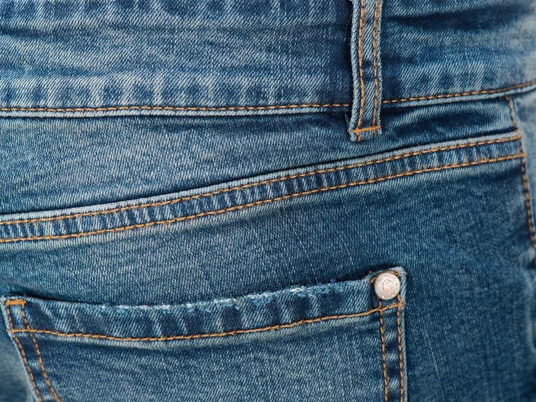 Nahaufnahme von blauem Denim mit einer Tasche und Nähten.