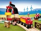 Ein roter BRIO Zug mit einem Wagen, einem Bauernhof und einem Traktor auf einer Holzbahn.