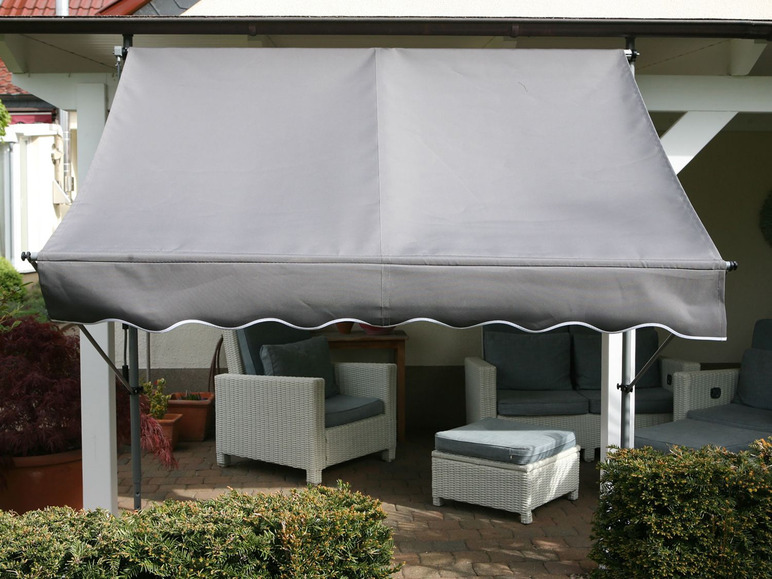 Ein grauer Sonnenschirm mit weißen Rattanstühlen und einem Hocker.