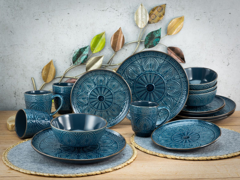 Ein Set blaues Geschirr mit einem gravierten Design, darunter Teller, Schalen und Becher.